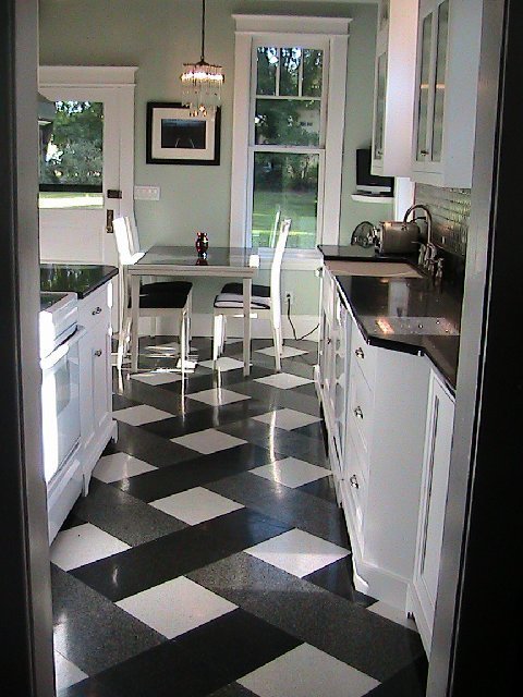 Kitchen after it's Tom Newman inspired makeover with a plaid tile floor, black counter top, white cabinets, mint walls and stainless appliances