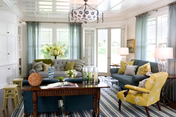 Living room with a gingham sofa, striped rug, blue armchairs, a yellow and white armchair, a blue sofa, sheer gingham curtains, a white and blue light and a coffered ceiling