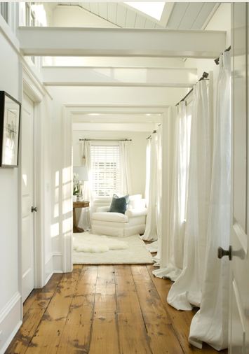 Hallway with natural wood floor leading to a white bedroom