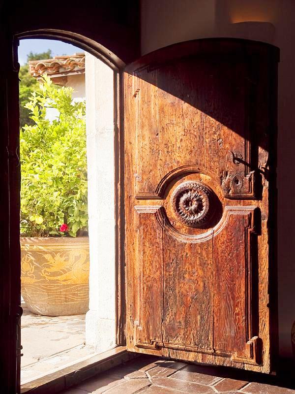 Carved, arched front door to a Montecito mansion with terra cotta tile floor