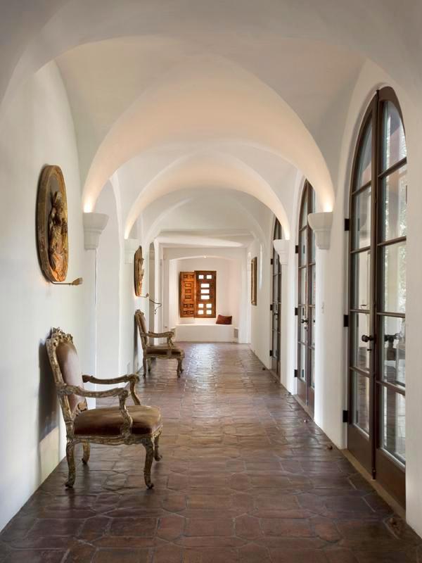 Hallway in a Montecito mansion with vaulted ceiling, arched doors and saltillo tile floor