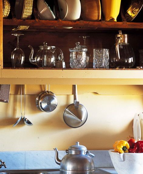 Close up of the stove, the yellow walls, and the yellow shelves with natural wood back