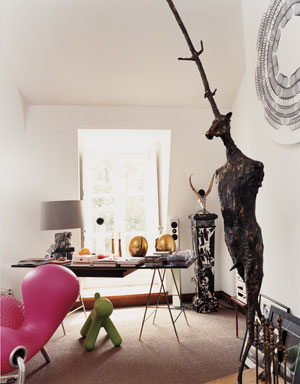 Yves Gastou's home office with a black desk on thin metal legs, a large window and lots of modern art sculptures