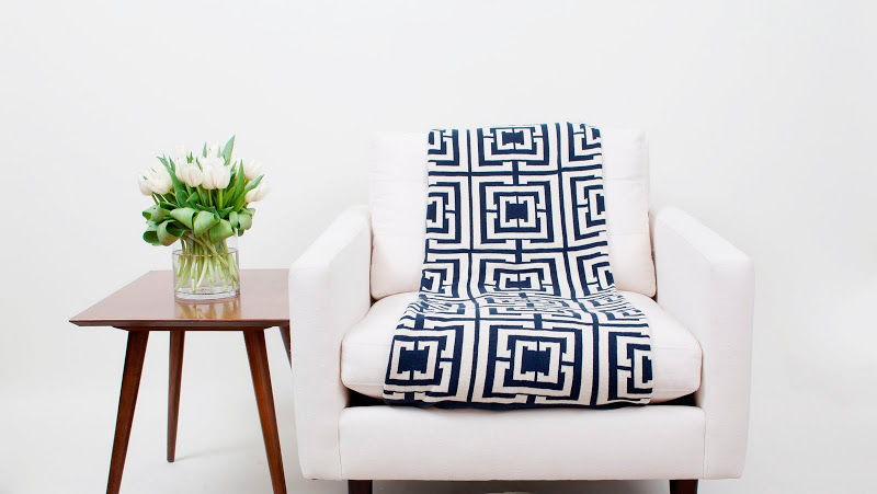 COCOCOZY Logo cotton knit reversible throw in navy on a white chair next to some beautiful Belgian tulips