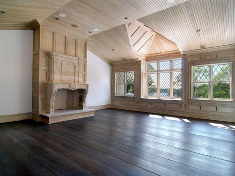 Master bedroom with light wood paneling and ceiling, wood floor and a fireplace