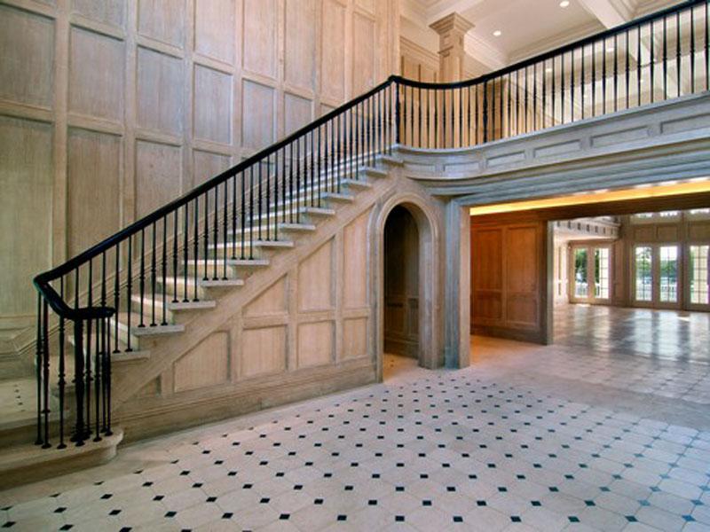 Foyer with French chalked wood paneling, black staircase railing and tile floor