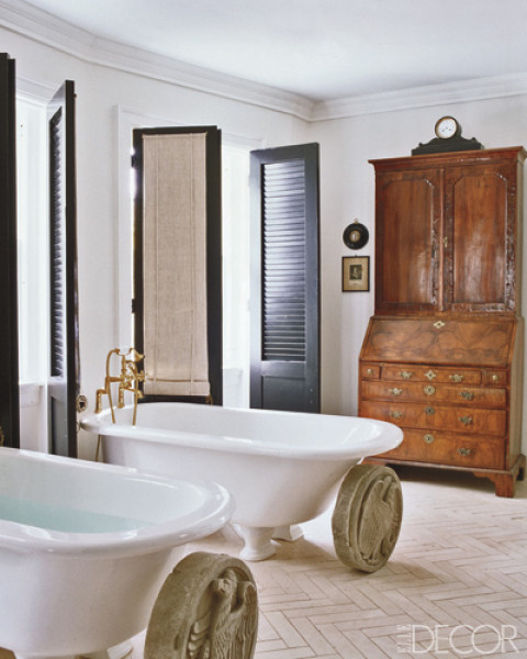 Bathroom with herringbone tile floor, two stand alone tubs, black doors and large roman coines