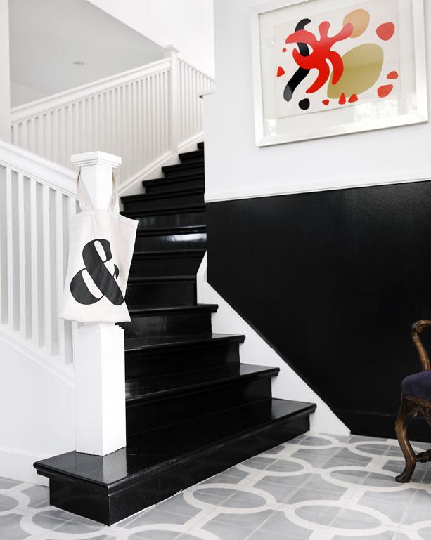 Foyer with a black staircase with white trimming and grey and white cement Moroccan tiles by Popham Designs