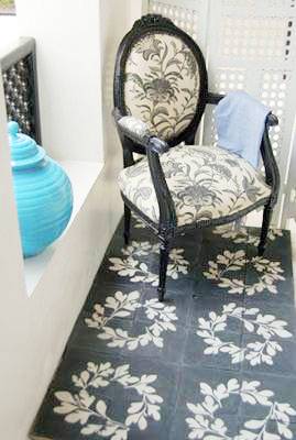 Black and white cement Moroccan tiles with a laurel crown print. On top of them is a black Louis XIV chair