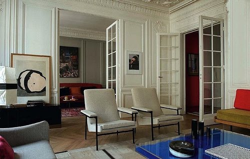 Living room with Yves Klein's Table Bleue, white walls with decorative moulding, French doors, herringbone wood floors, two armchairs and dueling sofas