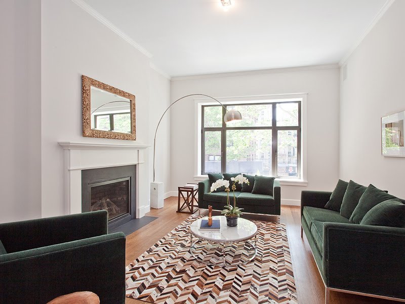 Living room in a LEED certified townhouse with fireplace, brown, white and black chevron printed rug, green sofas and an Arco floor lamp