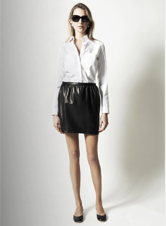 Model wearing a black pleather skirt and white button down from The Row