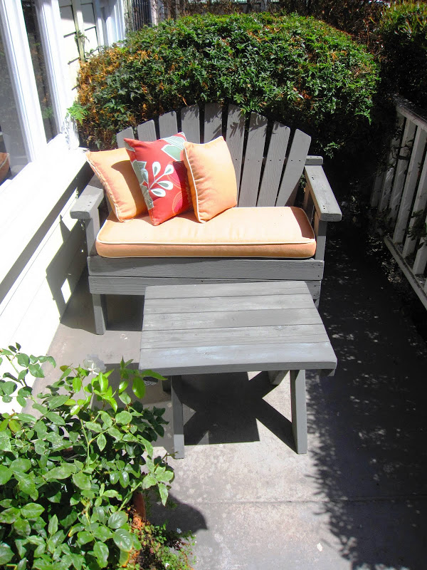 Grey Adirondack love seat with orange seat cushion on a front porch in Venice Beach, CA