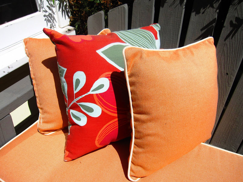 Close up of the orange floral accent pillows on a grey Adirondack love seat on the front porch of a cottage in Venice Beach, CA
