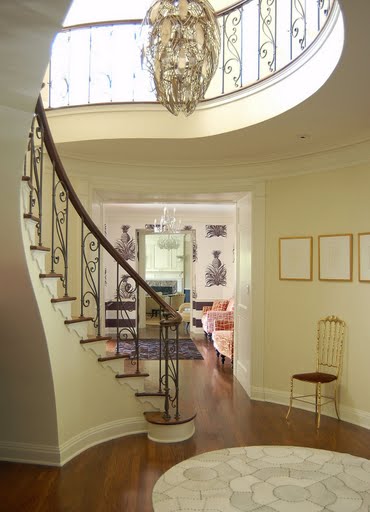Foyer in a restored Regency home by Kevin Oreck with a spiral staircase and chandelier