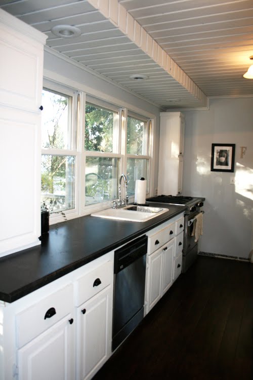Angela of Fixing it Fancy's kitchen after her remodeling with white cabinets and drawers, walnut floor and stainless appliances