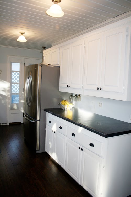 Angela of Fixing it Fancy's kitchen after the remodeling with white cabinets and dark walnut floor
