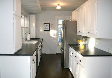 Kitchen in Angela of Fixing it Fancy's home with white cabinets and drawers, dark wood floor and black countertops