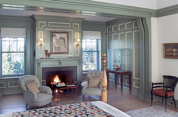 Cozy fireplace seating area in a grey-blue bedroom with white paneling trimmed in white by Peter Pennoyer 