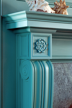 Detail of carved woodwork on a fireplace mantel in a blue library designed by Peter Pennoyer 