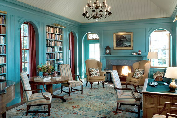Blue library in a home designed by Peter Pennoyer with arched windows, a fireplace, classic furnishings and a beadboard ceiling