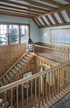 Exposed beam angled ceiling and more carved woodwork on the railing of the second floor landing in a home by Peter Pennoyer